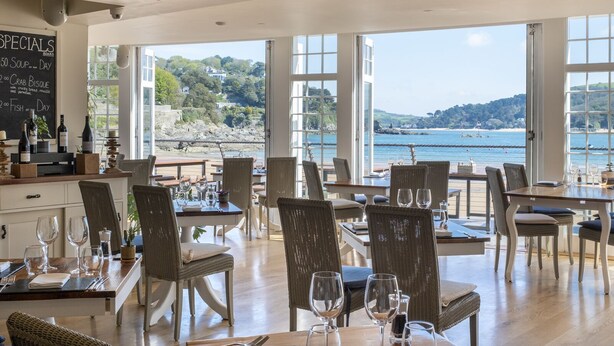 A restaurant with a view of the sea, wicker chairs, and a chalkboard menu. - South Sands Hotel (Salcombe)