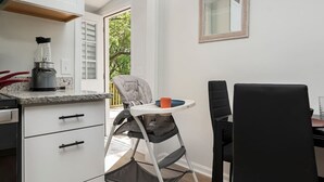 Une cuisine compacte équipée d’un mixeur, d’une chaise haute et d’une table à manger.