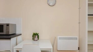 A kitchenette with a microwave, a small potted plant, and a white table with chairs. - Vivid Apartment in Central London (London)