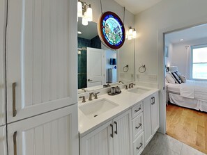 A bathroom with a double sink, a large mirror, and a stained glass window.