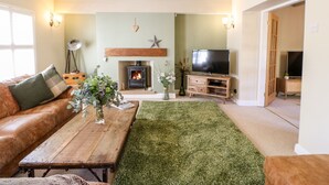 A cozy living room with a fireplace, a television, and a green artificial turf rug.