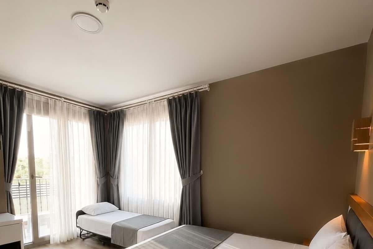 A hotel room with two beds, a desk, and a window with curtains.