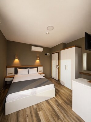 A hotel room with a bed, bedside tables, an air conditioning unit, a wardrobe, and a television. - AURORA SIĞACIK HOTEL (Seferihisar)