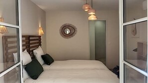 Een slaapkamer met een bed, twee bedlampen, een spiegel en een deur.