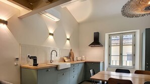 Een moderne keuken met een centraal eiland, inbouwapparatuur en een eethoek met een groot raam.