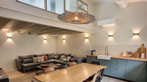 Een moderne keuken met een eethoek, met een houten tafel en stoelen, een inbouwoven en een spoelbak.
