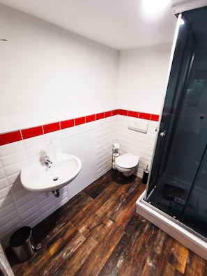 A bathroom with a white sink, toilet, and a glass shower enclosure. - Ferienhäuser - Pappelallee (Biesenthal)