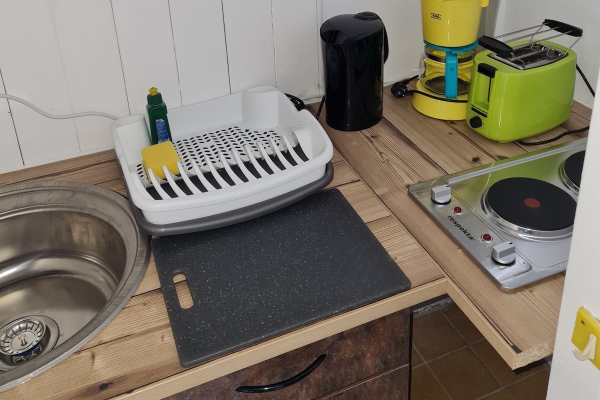 Eine Küche mit Spüle, Herd, Kaffeemaschine, Toaster und Geschirrgestell.