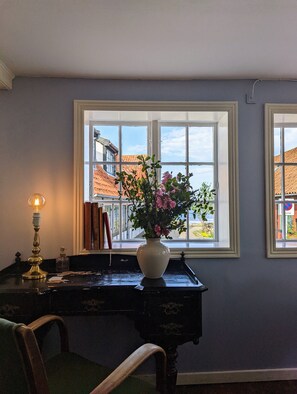 A room with a desk, a vase with flowers, and a lamp. - Næsgaarden Pensionat (Allinge)