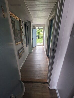 A hallway with wooden flooring, a door leading to a garden, and framed pictures on the walls. - Næsgaarden Pensionat (Allinge)