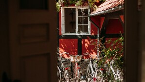Une porte ouverte donnant sur une cour où l’on aperçoit des vélos et, au fond, un bâtiment rouge.