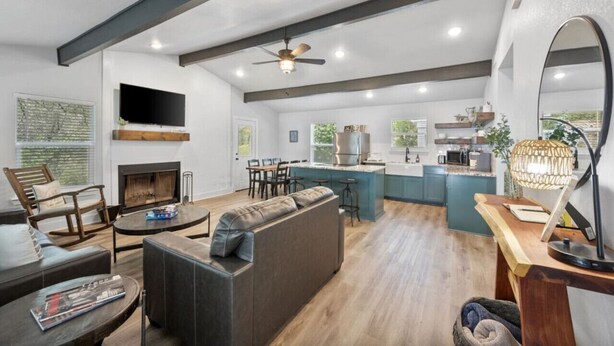 A modern living room with a fireplace, a large sofa, and a television. - Lakefront, Kayaks, 2.5 acres, March Dates Open (Granbury)
