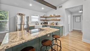 A modern kitchen with a large island, stainless steel appliances, and wooden bar stools. - Lakefront, Kayaks, 2.5 acres, March Dates Open (Granbury)