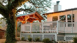 A wooden deck with a lattice railing, a covered seating area, and a building with windows. - Lakefront, Kayaks, 2.5 acres, March Dates Open (Granbury)