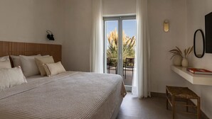 A bedroom with a large bed, a balcony with a view of tall plants, and a small table with a book. - Nysis Koufonisia (Naxos)