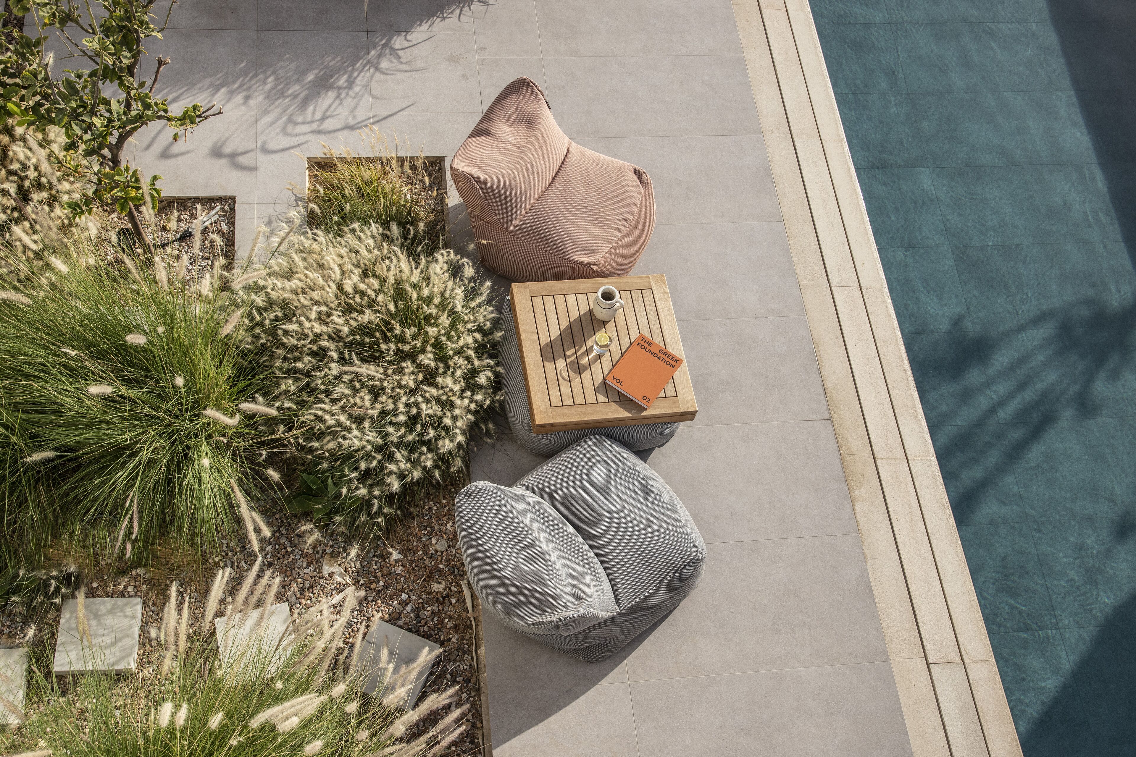 A poolside seating area with a table, cushions, and a book.