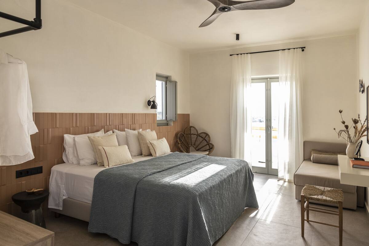 A bedroom with a bed, a desk, a chair, and a window with curtains.