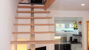Un interior moderno con una escalera de madera que lleva a una zona superior.