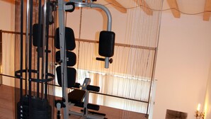 Un gimnasio con techo de madera, equipo de ejercicio y un estante montado en la pared.