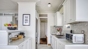 A modern kitchen with white cabinetry, a microwave, and a fruit bowl on the counter. - Monastiraki Stylish Loft W/ Acropolis View/Bathtub (Athina)