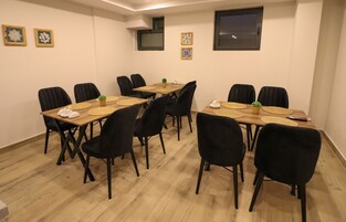 Un salón de conferencias con una mesa de madera, sillas negras y decoración en las paredes.