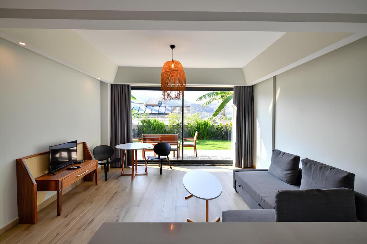 A modern living room with a sofa, a TV, a wooden desk, and a dining area.