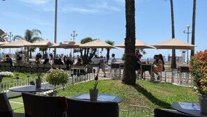 Un espacio al aire libre con mesas y sillas, sombrillas y vistas al mar.