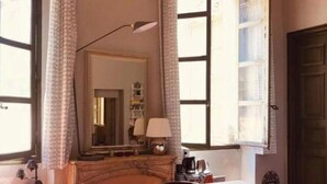 Een kamer met een houten tafel, een bankje, een lamp en een spiegel.