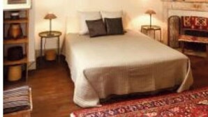 Een slaapkamer met een bed, nachtkastjes, een open haard en een boekenkast.