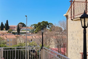 Un balcon avec une balustrade, un lampadaire et, au fond, un bâtiment avec un toit recouvert de tuiles.