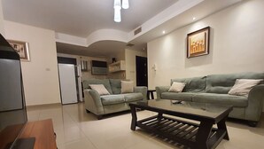 A modern living room with two sofas, a coffee table, and a kitchen in the background. - Abdoun Panorama (Amman)