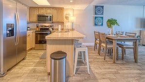 A modern kitchen with stainless steel appliances, wooden cabinets, and a central island. - DIRECT BEACHFRONT! SWIMMING POOL! (Indian Shores)