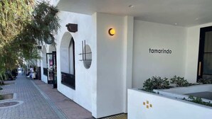 Un edificio moderno con fachada blanca, un área de recepción con un logotipo y un camino con pavimento estampado.
