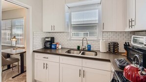 Una cocina moderna con armarios blancos, un lavamanos doble y un microondas.