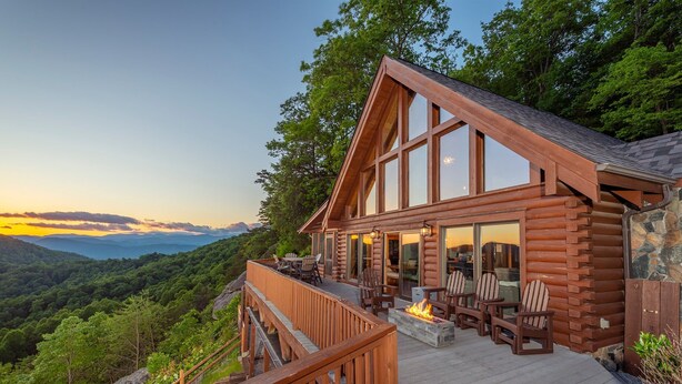 Une cabane en rondins dotée d’une terrasse, d’un espace salon extérieur et d’un foyer.