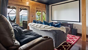 Un salon chaleureux avec un grand écran, des sièges confortables et une vue sur l’extérieur.