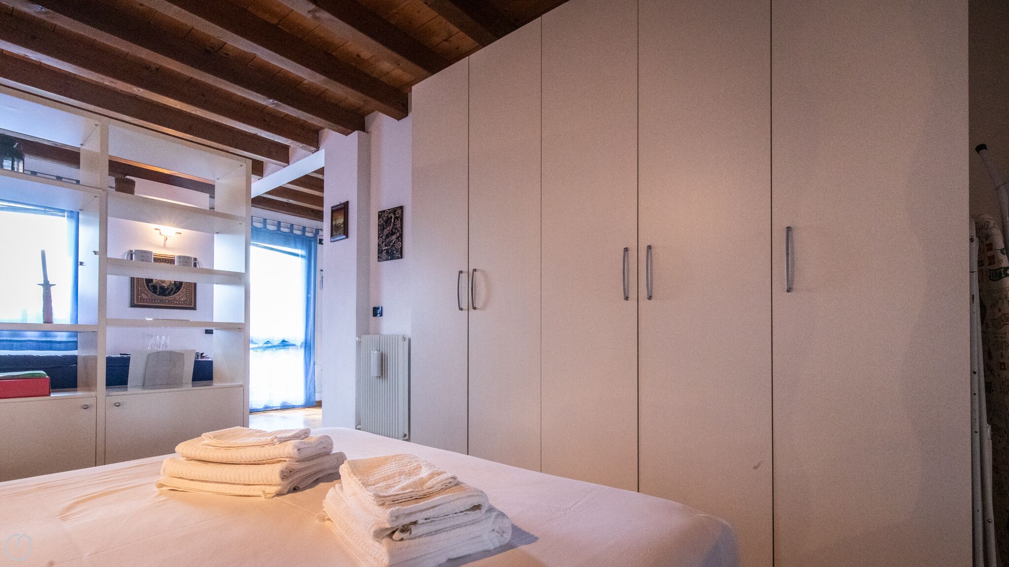 A bedroom with a bed, a wardrobe, and a shelf unit.