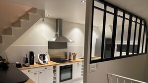 A modern kitchen with a built-in stove, oven, and stainless steel range hood. - Charming house located on the marina (Bénodet)