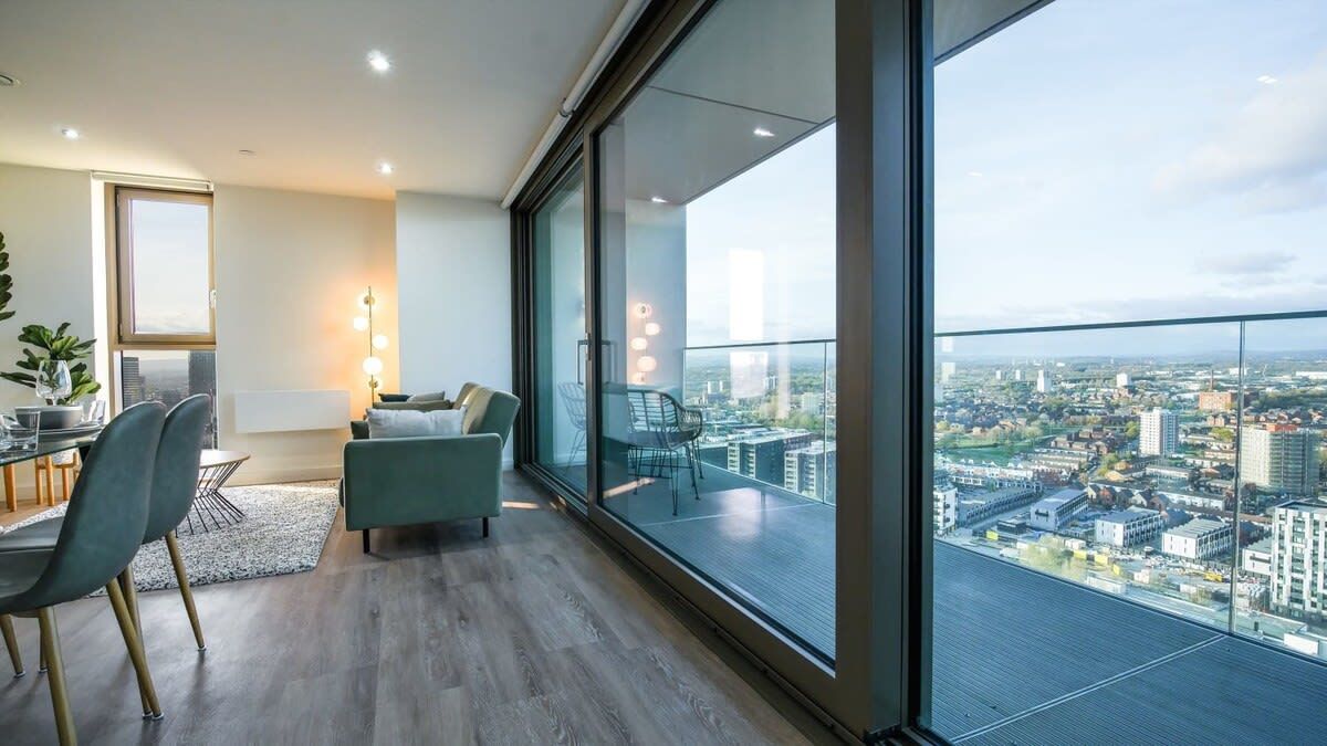 Un apartamento moderno con un balcón grande, comedor y vistas a la ciudad.