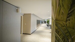 A hallway with a reception desk, a plant, and a door on the left.