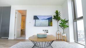 A modern interior with a round table, a mounted TV, and potted plants.