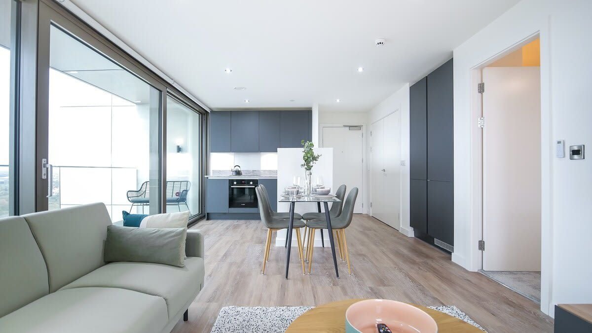 A modern apartment with a dining area, kitchen, and a balcony.