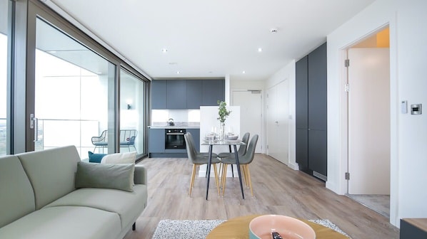 A modern apartment with a dining area, kitchen, and a balcony.