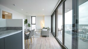 A modern apartment with a kitchen, dining area, and a balcony with a city view.