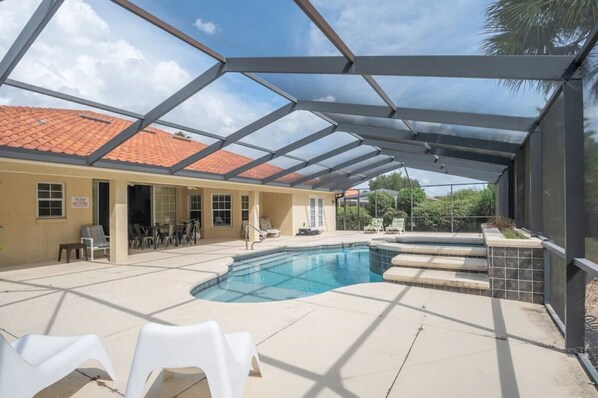 A covered outdoor swimming pool with a tiled roof, lounge chairs, and a patio area. - Luxury with a pool Su (Inverness)