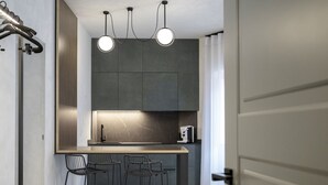Une cuisine moderne dotée d’un îlot central, de deux tabourets de bar et d’un éclairage suspendu.