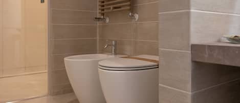 A modern bathroom with two toilets, a sink, and a towel rack.