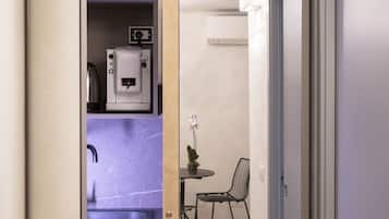 A modern kitchen with a built-in microwave, a sink, and a small dining area with a chair and table.