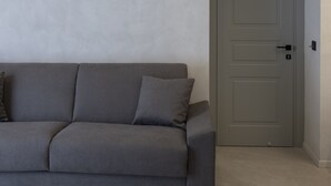 Un salon moderne avec un canapé gris et une porte fermée.