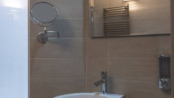 A bathroom with a white sink, a mirror, and a towel rack.